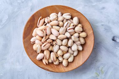 Beyaz arka plan, üstten görünüm, yakın çekim, seçici odak ahşap bir tabakta tuzlu fıstık.