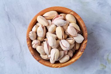 Beyaz arka plan, üstten görünüm, yakın çekim, seçici odak ahşap bir tabakta tuzlu fıstık.