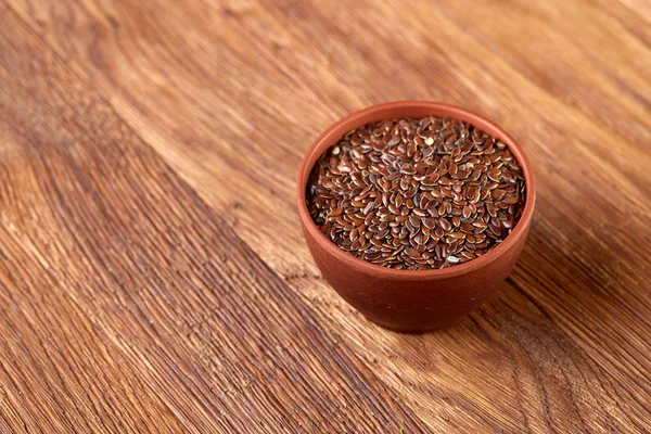 Un cuenco de cerámica volcado con semillas de lino sobre un fondo rústico, primer plano, poca profundidad de campo, enfoque selectivo — Foto de Stock
