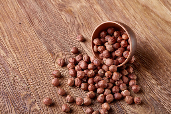 Орешки в опрокинутой керамической чаше на деревянном фоне с копировальным пространством, вид сверху, выборочная фокусировка
.