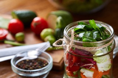 Kavanoz ve tablo, seçici odak, yakın çekim kesme tahtası üzerinde taze sebzeler lezzetli sebze salatası