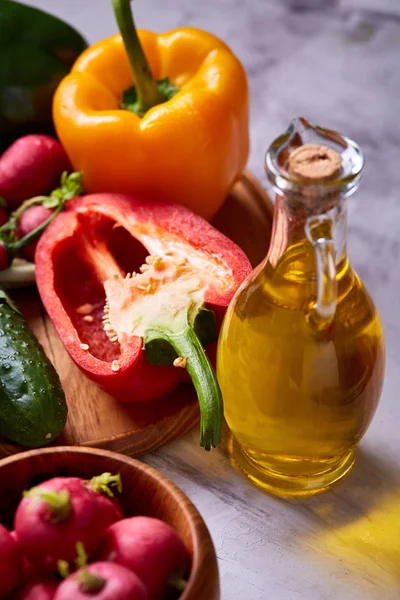 Delicious masih hidup dengan minyak zaitun emas dalam botol kaca di antara sayuran segar, close-up, fokus selektif — Stok Foto