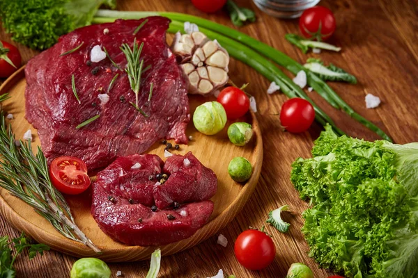 Natureza morta da carne crua com legumes em chapa de madeira sobre fundo branco, vista superior, foco seletivo — Fotografia de Stock