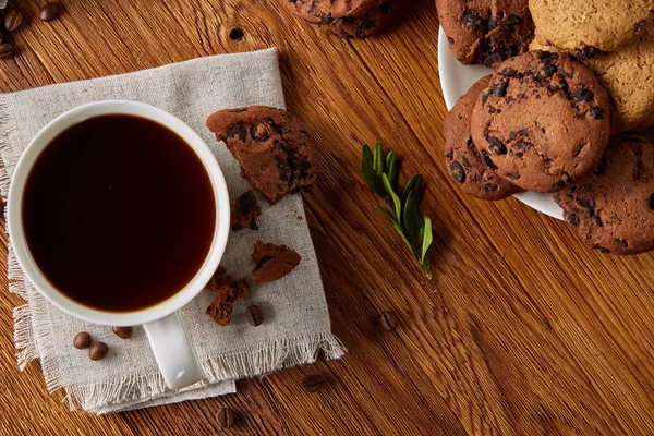 Coffee cup, jar with coffee beans, cookies over rustic background, selective focus, close-up, top view — Stock Photo, Image