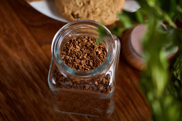 Открытая банка растворимого кофе расположены на Woden стол, вид сверху, крупным планом, избирательный фокус
.