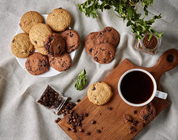 Coffee cup, jar with coffee beans, cookies over rustic background, selective focus, close-up, top view — Stock Photo, Image