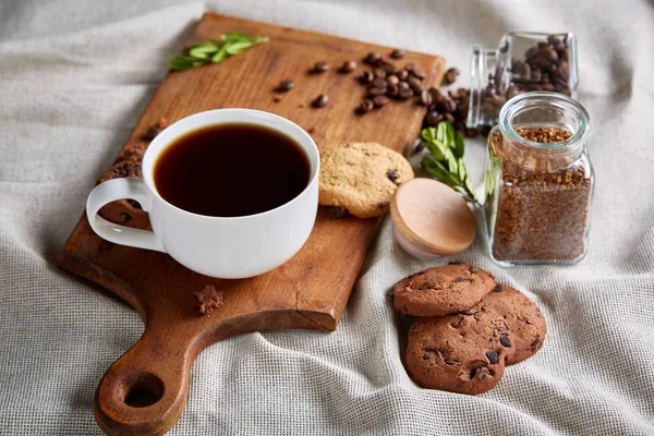 Coffee cup, jar with coffee beans, cookies over rustic background, selective focus, close-up, top view — Stock Photo, Image