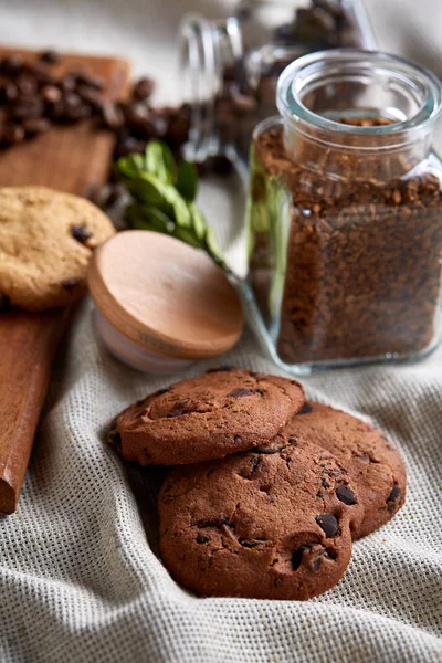 Roasted coffee beans get out of overturned glass jar on homespun tablecloth, selective focus, side view — Stock Photo, Image