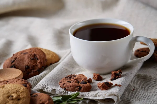 Café de la mañana en taza blanca, galletas de chispas de chocolate en el primer plano de la tabla de cortar, enfoque selectivo — Foto de Stock