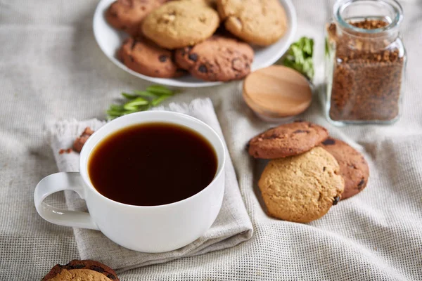 Café de la mañana en taza blanca, galletas de chispas de chocolate en el primer plano de la tabla de cortar, enfoque selectivo — Foto de Stock