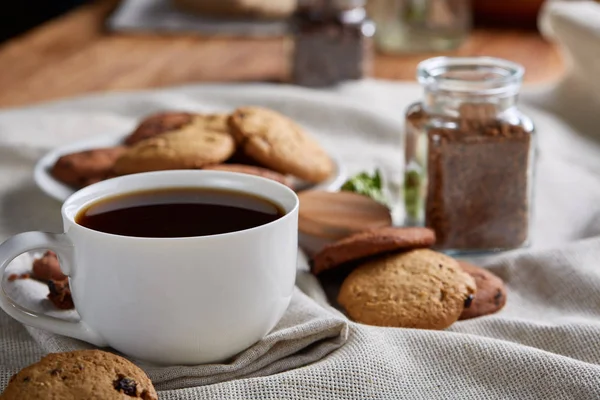 Café de la mañana en taza blanca, galletas de chispas de chocolate en el primer plano de la tabla de cortar, enfoque selectivo — Foto de Stock