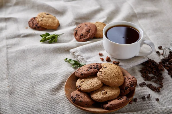 Café de la mañana en taza blanca, galletas de chispas de chocolate en el primer plano de la tabla de cortar, enfoque selectivo — Foto de Stock