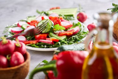 Yaratıcı taze sebze salatası ruccola, salatalık, domates ve beyaz plaka, seçici odak üzerinde raddish