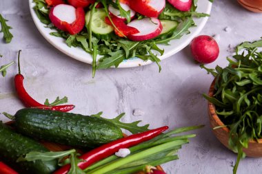 Yaratıcı taze sebze salatası ruccola, salatalık, domates ve beyaz plaka, seçici odak üzerinde raddish
