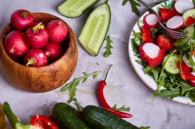 Yaratıcı taze sebze salatası ruccola, salatalık, domates ve beyaz plaka, seçici odak üzerinde raddish