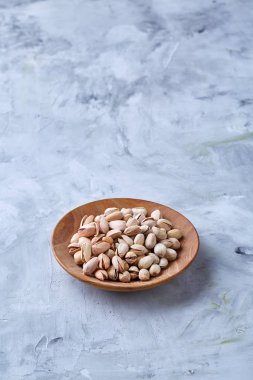 Beyaz arka plan, üstten görünüm, yakın çekim, seçici odak ahşap bir tabakta tuzlu fıstık.