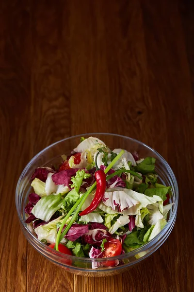 Salade de légumes frais servie dans un bol en verre sur fond de bois foncé, mise au point sélective, faible profondeur de champ — Photo