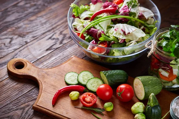 stock image Fresh vegetable salad and ripe veggies on cutting board over wooden background, close up, selective focus