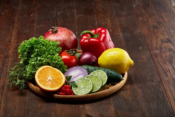 Still life of fresh organic vegetables on wooden plate over wooden background, selective focus, close-up — Stock Photo, Image