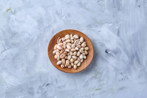 Beyaz arka plan, üstten görünüm, yakın çekim, seçici odak ahşap bir tabakta tuzlu fıstık.