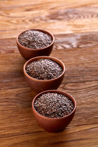 Flax seeds in wooden bowl on rustic wooden background, top view, selective focus — Stock Photo, Image