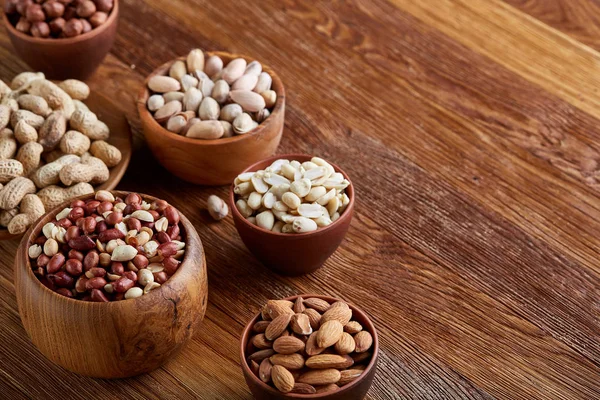 A composition from different varieties of nuts in a wooden bowls on rustic background, close-up, shallow depth of field