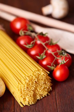 Pişmemiş makarna, domates ahşap arka plan, üstten görünüm, yakın çekim, seçici odak