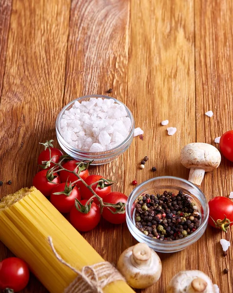 Rohe Nudeln, Tomaten auf Holzgrund, Draufsicht, Nahaufnahme, selektiver Fokus — Stockfoto