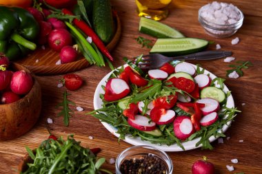Yaratıcı taze sebze salatası ruccola, salatalık, domates ve beyaz plaka, seçici odak üzerinde raddish