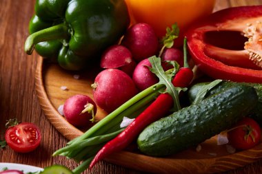 Yaratıcı taze sebze salatası ruccola, salatalık, domates ve beyaz plaka, seçici odak üzerinde raddish