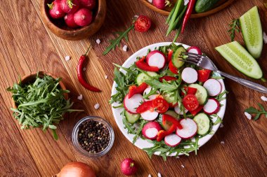 Yaratıcı taze sebze salatası ruccola, salatalık, domates ve beyaz plaka, seçici odak üzerinde raddish