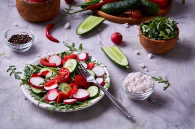Yaratıcı taze sebze salatası ruccola, salatalık, domates ve beyaz plaka, seçici odak üzerinde raddish