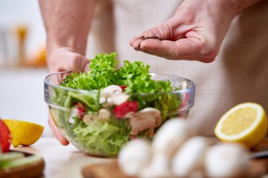 Man cooking at kitchen making healthy vegetable salad, close-up, selective focus. clipart