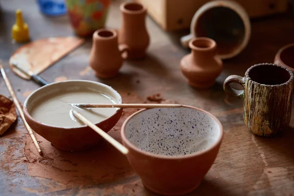 Pędzle malarskie zanurzyć się w ceramicznej miski na blacie w warsztacie potter, zbliżenie, Selektywny fokus. — Zdjęcie stockowe