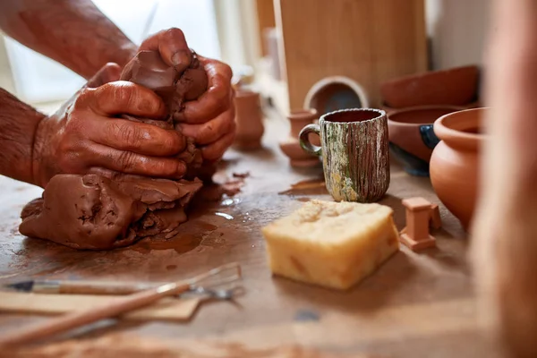 Hands of male potter molding a clay in pottery workshop, close-up, selective focus