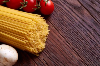 Pişmemiş makarna, domates ve baharat ahşap arka plan, üstten görünüm, yakın çekim, seçici odak