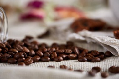 Kavrulmuş kahve çekirdekleri devrilmiş Cam Kavanoz saf masa örtüsü, seçici odak, yan görünüm elde