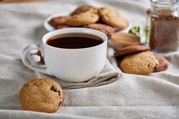 Café de la mañana en taza blanca, galletas de chispas de chocolate en el primer plano de la tabla de cortar, enfoque selectivo — Foto de Stock