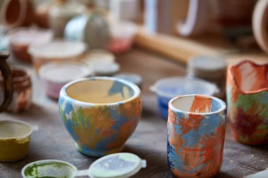 Yakın çekim çeşitli boya kupalar ve fırça tutucu tezgah, seçici odak, yan görünüm.