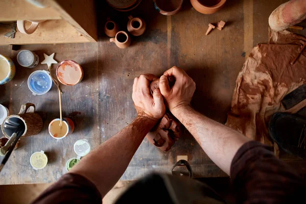 Volwassen mannelijke potter meester de kleiplaat modelleren op potters wiel. Bovenaanzicht, close-up, handen alleen. — Stockfoto