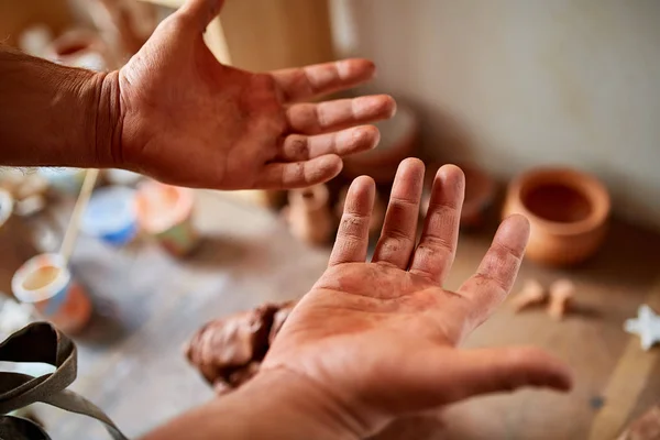 Adult male potter master modeling the clay plate on potters wheel. Top view, closeup, hands only. — Stock Photo, Image