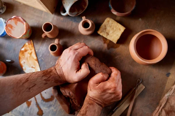 Volwassen mannelijke potter meester de kleiplaat modelleren op potters wiel. Bovenaanzicht, close-up, handen alleen. — Stockfoto