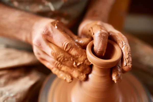 Adult male potter master modeling the clay plate on potters wheel. Top view, closeup, hands only. — Stock Photo, Image