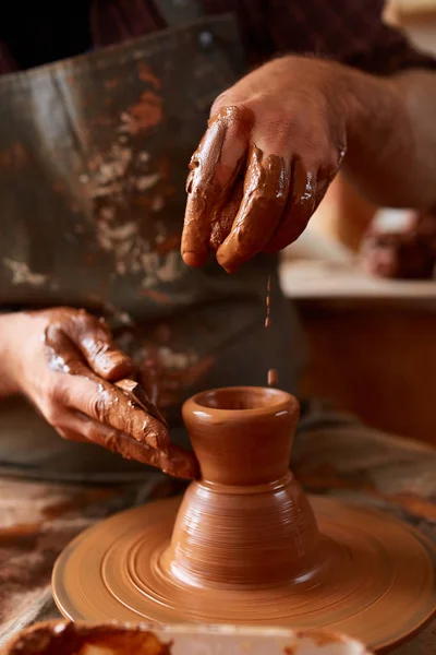 Portrait of a male potter in apron molds bowl from clay, selective focus, close-up
