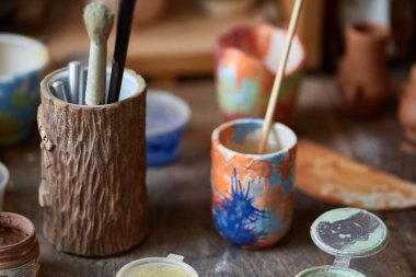 Yakın çekim çeşitli boya kupalar ve fırça tutucu tezgah, seçici odak, yan görünüm.