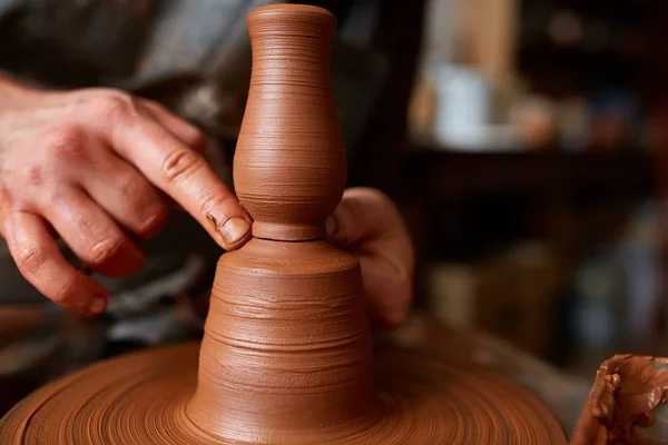 Gros plan mains d'un potier masculin dans un tablier faisant un vase d'argile, mise au point sélective — Photo