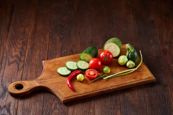 Свежий овощной салат и спелые овощи на разделочной доске на белом фоне, закрыть, избирательный фокус — стоковое фото