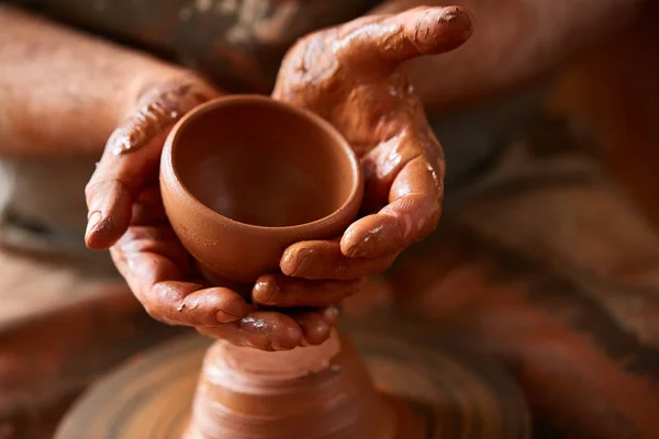 Primo piano mani di un vasaio maschio in grembiule rendendo un vaso di argilla, messa a fuoco selettiva — Foto Stock