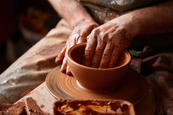 Gros plan mains d'un potier masculin dans un tablier faisant un vase d'argile, mise au point sélective — Photo