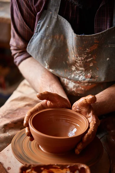 Portret van een mannelijke potter in schort mallen kom uit klei, selectieve aandacht, close-up — Stockfoto